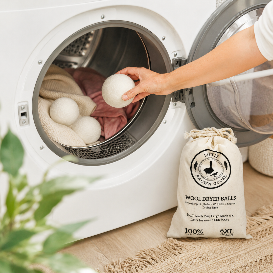 Six reusable wool dryer balls beside fresh towels and Little Brown Goose laundry products