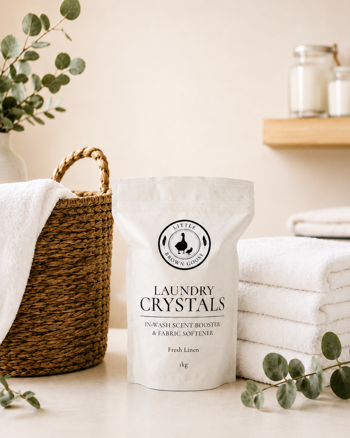 Little Brown Goose Laundry Crystals beside a laundry basket and fresh towels