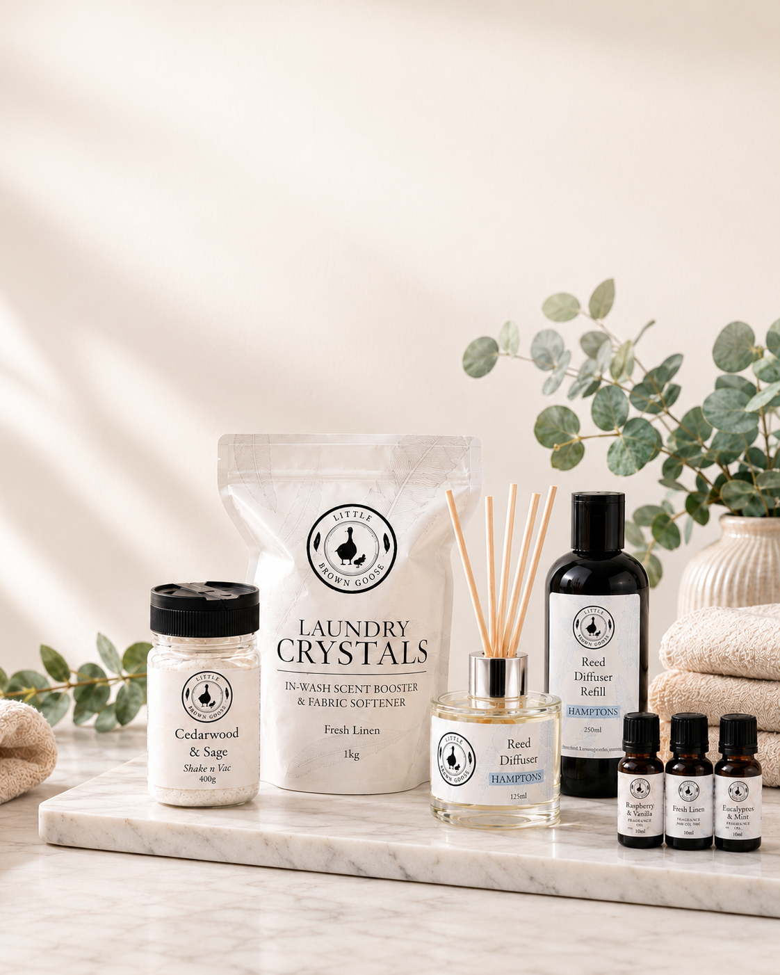 Little Brown Goose low-tox home essentials arranged with Laundry Crystals, Shake n Vac, reed diffuser and fragrance oils